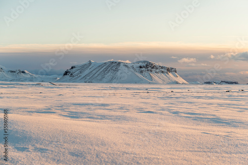 montañas de tierra volcánica nevadas, rodeadas de campos de nieve con el cielo azul claro e iluminadas por las primeras luces del día © carles