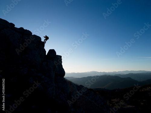 silhouette of mountaineer descending from cliff