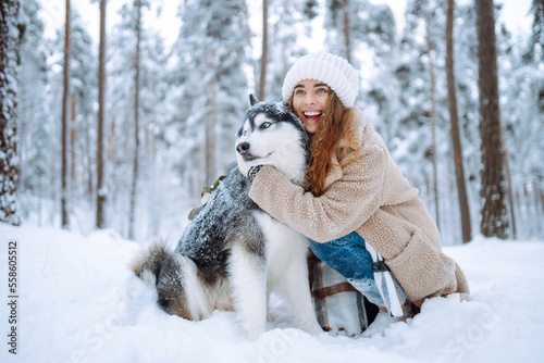 Happy woman walking her dog in the winter and both explore the snow together in playful mood. Friendship  pet and human.