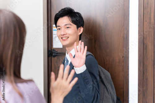 出勤する夫と玄関で見送る妻（夫婦・カップル・行ってらっしゃい・バイバイ）