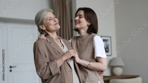 adult daughter and her gray-haired mother embracing look at the camera with smiles on their faces