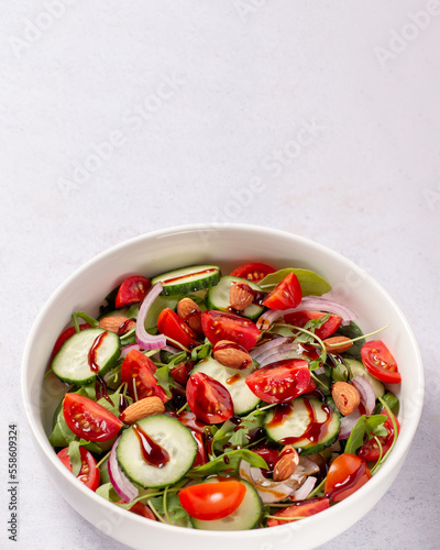 Healthy salad with spelt, oranges, pomegranate seeds. greens and nuts on light background, minimal style