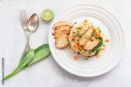 Fried rice with chicken breast has vegetable in plate on white table.