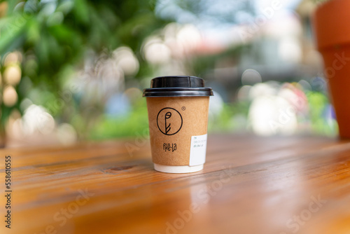 Closeup of blank craft paper coffee cup on the wood table. Space for you advertising. Horizontal mockup, blurred background