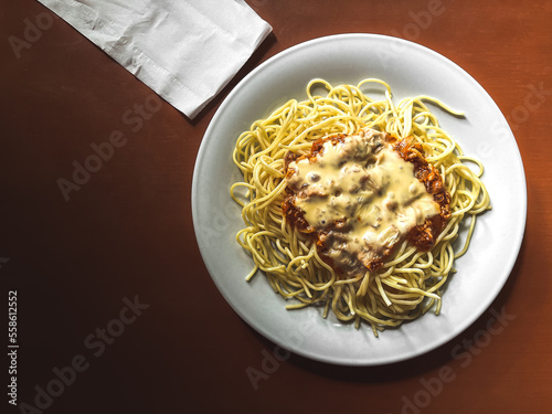 Unstirred spaghetti on a plate, accompanied by a tissue on a wooden table. photo