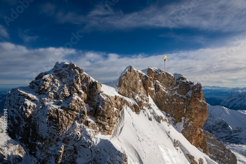 “Zugspitze“ peak with golden summit cross is the hightest mountain top in Germany on the border to Austria. Winter panorama above Garmisch-Partenkirchen with alpine scenery on a sunny december day. © ON-Photography