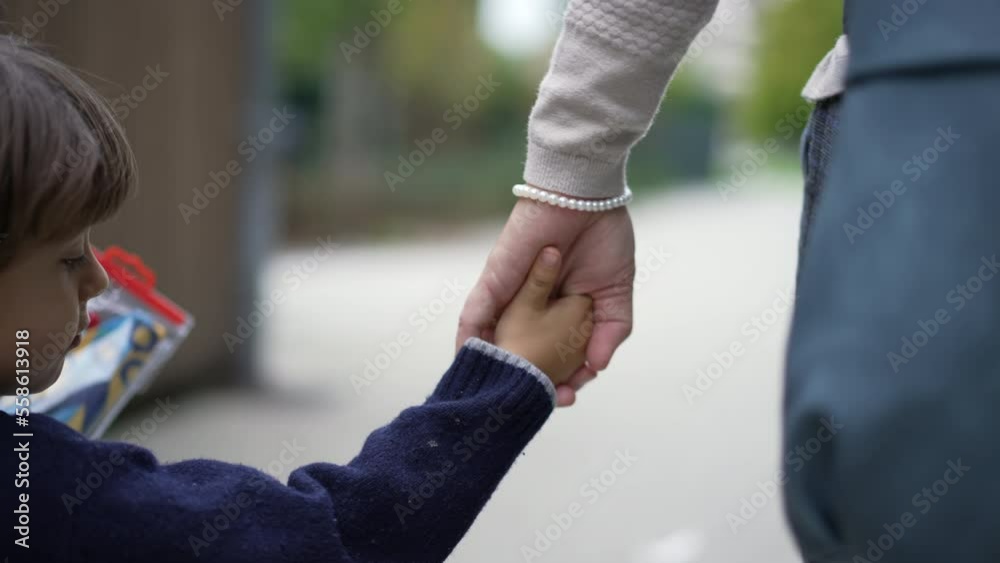 Closeup child and mother holding hands walking outside. Hand of parent and kid held together going for a walk together