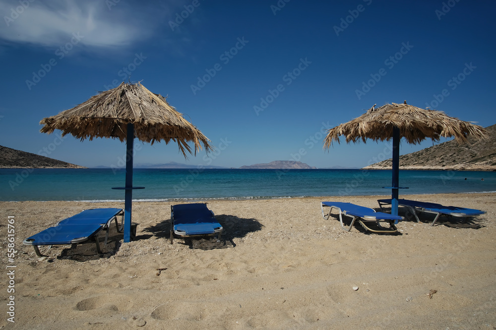 Sun beds and a sun umbrellas at the amazing beach of Agia Theodoti in Ios Greece
