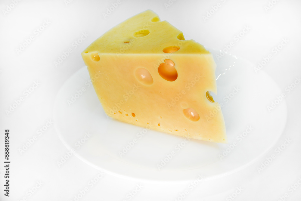 A large piece of cheese on a white background. A triangular piece of cheese with holes.