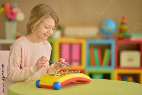 Beautiful girl playing musical instrument at home