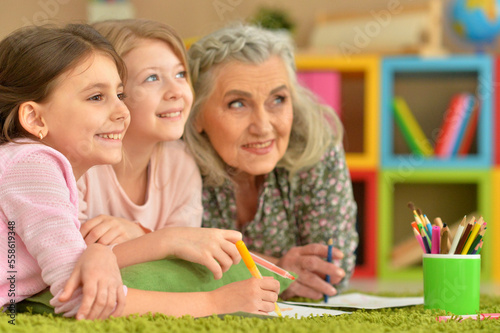 grandmother and granddaughters doing homework together at home