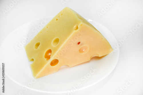 A large piece of cheese on a white background. A triangular piece of cheese with holes.