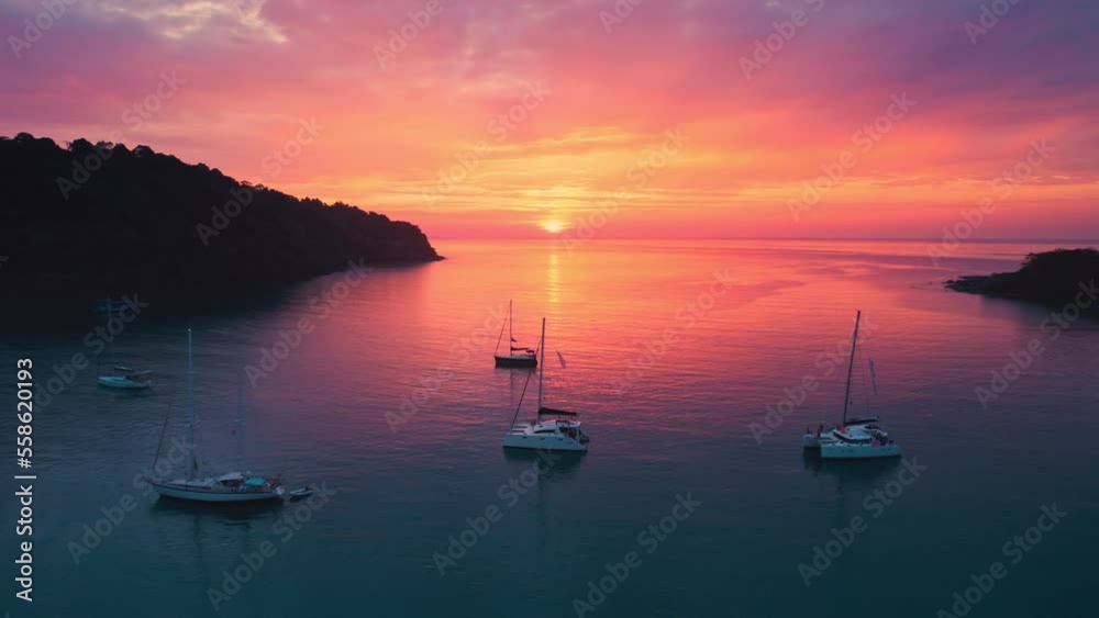 Aerial view of beautiful sunset over the tropical sea with sightseeing yacht cruise in summer