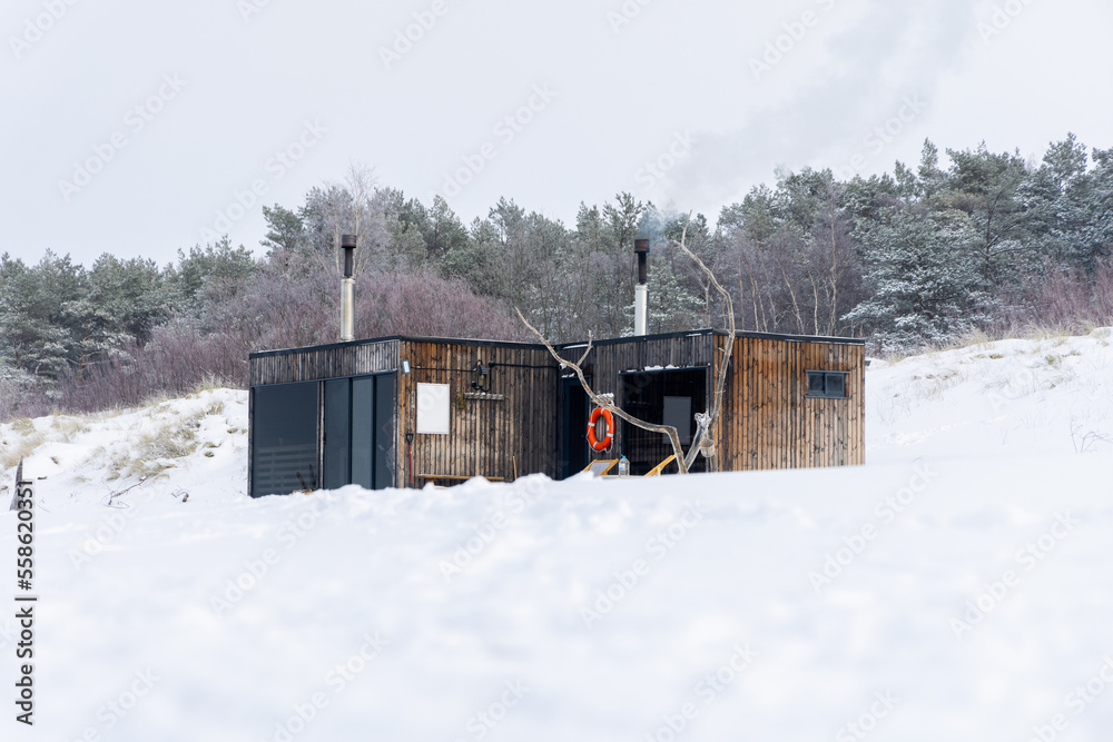 Φωτογραφία Wooden outdoor sauna with a smoke coming out of chimney on a beautiful cold snowy winter day at the Baltic sea