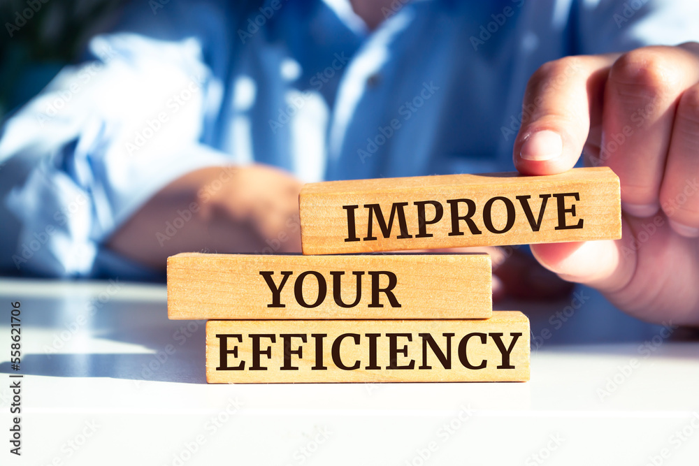 Closeup on businessman holding a wooden blocks with text 'IMPROVE YOUR EFFICIENCY', business concept Closeup on businessman holding a wooden blocks with text 'IMPROVE YOUR EFFICIENCY', business concept