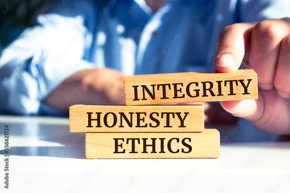 Closeup on businessman holding a wooden blocks with text 'integrity, HONESTY, ETHICS', business concept Closeup on businessman holding a wooden blocks with text 'integrity, HONESTY, ETHICS', business concept