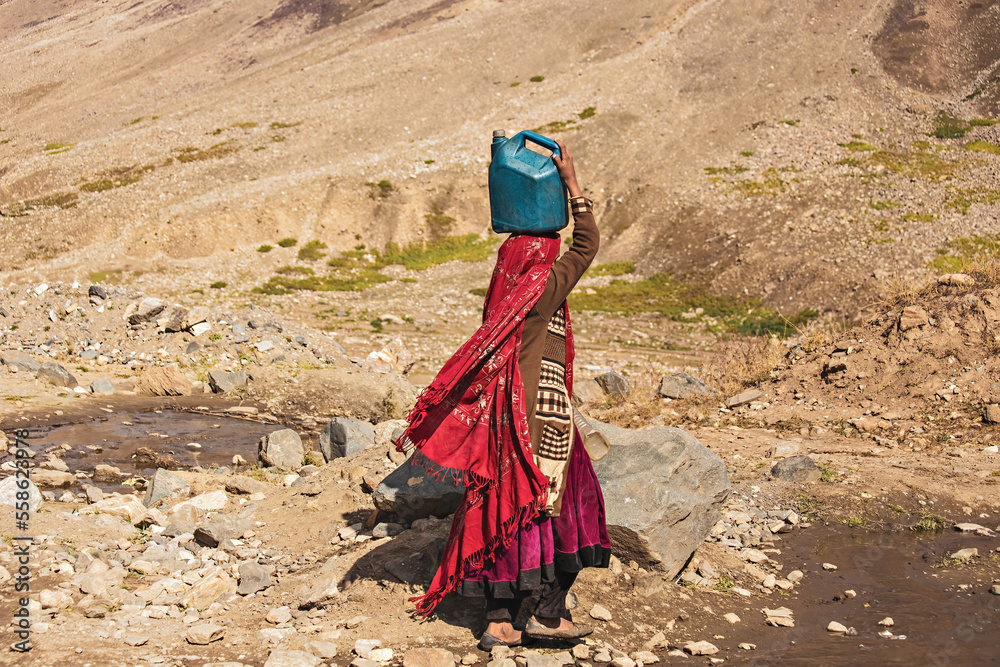 Pakistani woman with a jar of water on the head in the village in Northern Pakistan Pakistani woman with a jar of water on the head in the village in Northern Pakistan