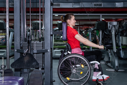 Woman in a wheelchair lifting weight in gym