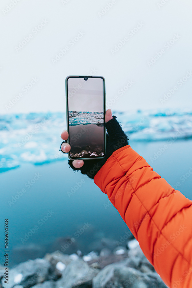 Man photographing a glacier with his smartphone.