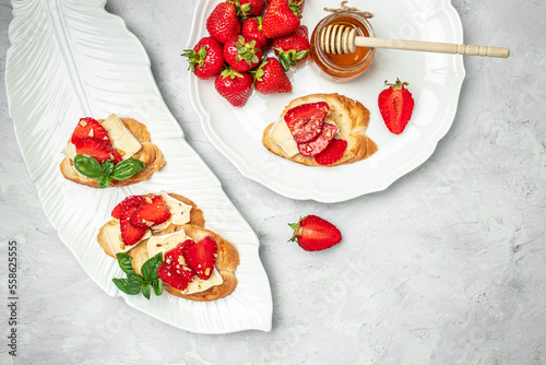 Crostini with strawberries, cheese camembert nuts and honey. top view