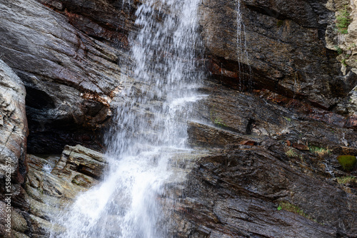 Mountainous alpine karst rocks washed with water with moss residues in splashes of water jets from Lillaz waterfall (Cascate di Lillaz) Aosta valley, Italy