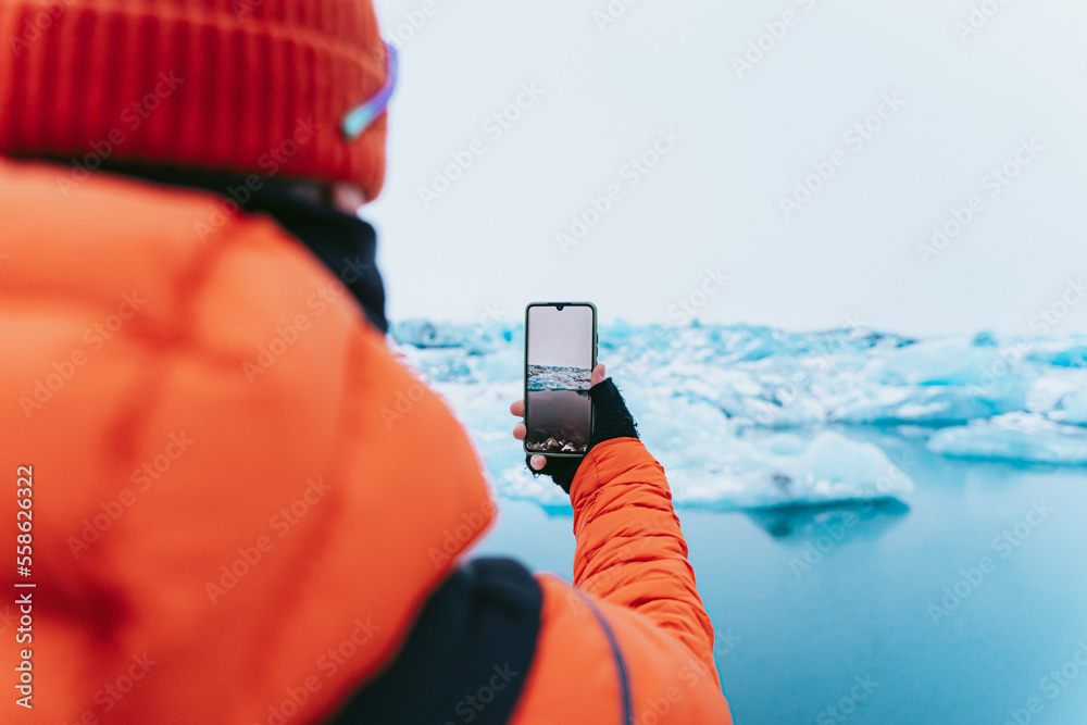 Man photographing a glacier with his smartphone.