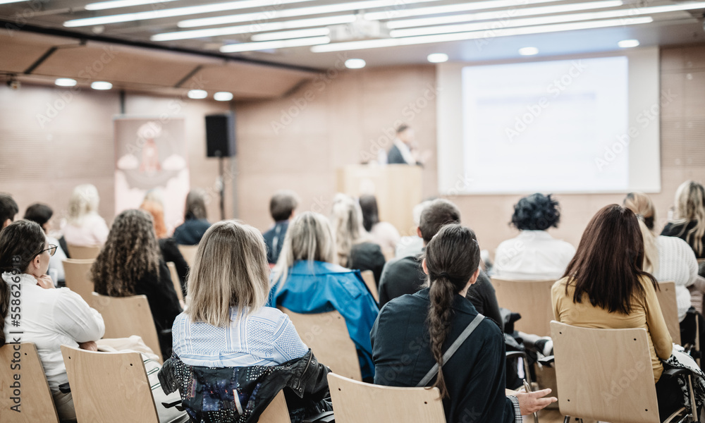 Obraz premium Speaker giving a talk in conference hall at business event. Rear view of unrecognizable people in audience at the conference hall. Business and entrepreneurship concept