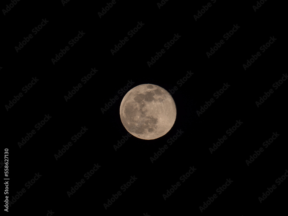 Close up of full moon seen with the telescope from northern hemisphere. Yellow brown tone. Black night sky background. Close up of full moon seen with the telescope from northern hemisphere. Yellow brown tone. Black night sky background.
