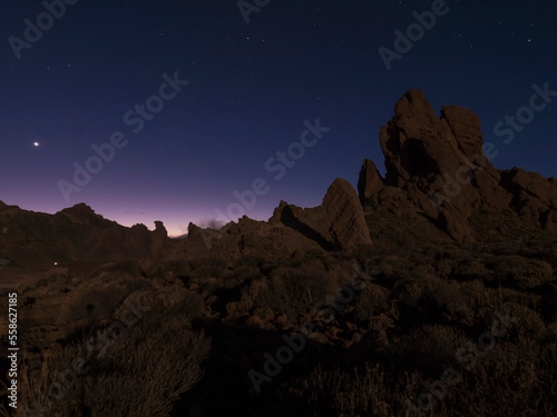 Long exposure night shot of Roques de Garcia volcanic rock formation at El Teide national park  early night winter sky with stars on pink blue glow. Tenerife Canary islands  Spain
