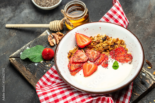Granola with yogurt with fresh strawberry, chia seeds and honey on a dark background. Delicious balanced food concept
