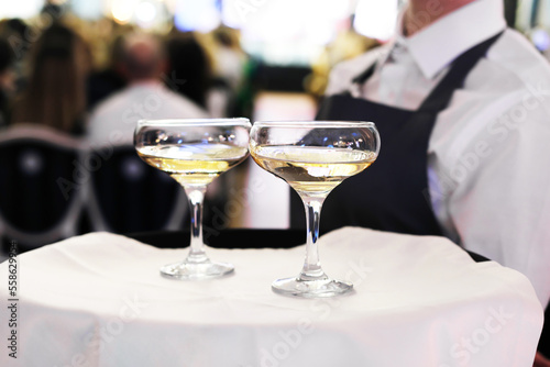 The waiter is holding a tray with two glasses of champagne. Catering for the event