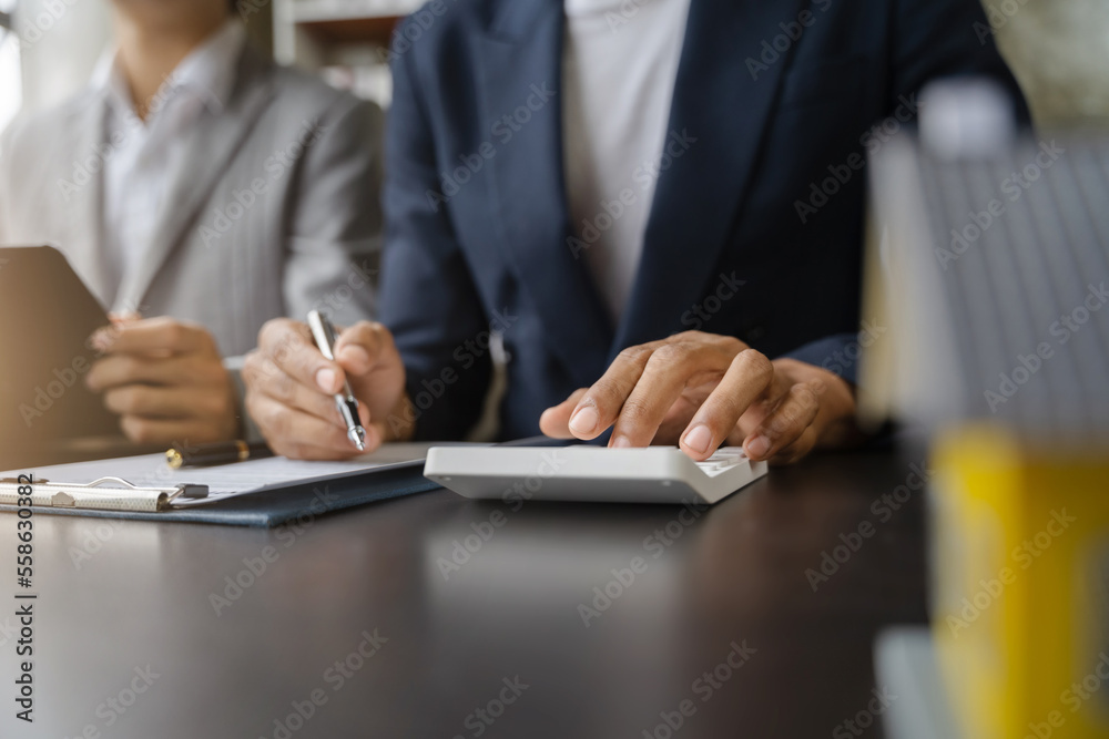 home loan officer uses a calculator with a house plan on a wooden table. home loan officer uses a calculator with a house plan on a wooden table.
