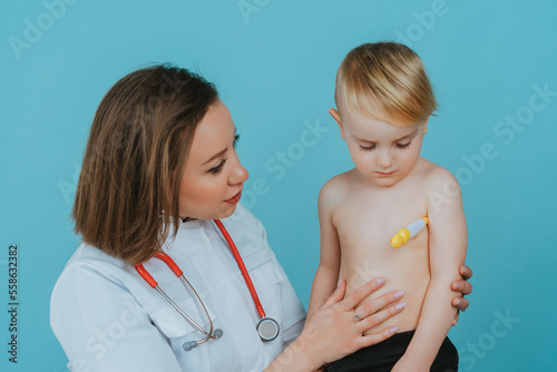 Woman doctor measures the temperature of a little boy