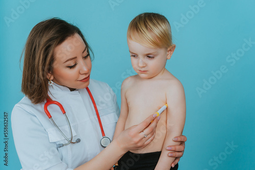Woman doctor measures the temperature of a little boy