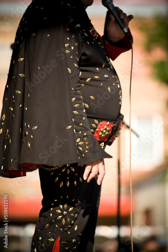Elvis impersonator in a black costume sings for the crowd.