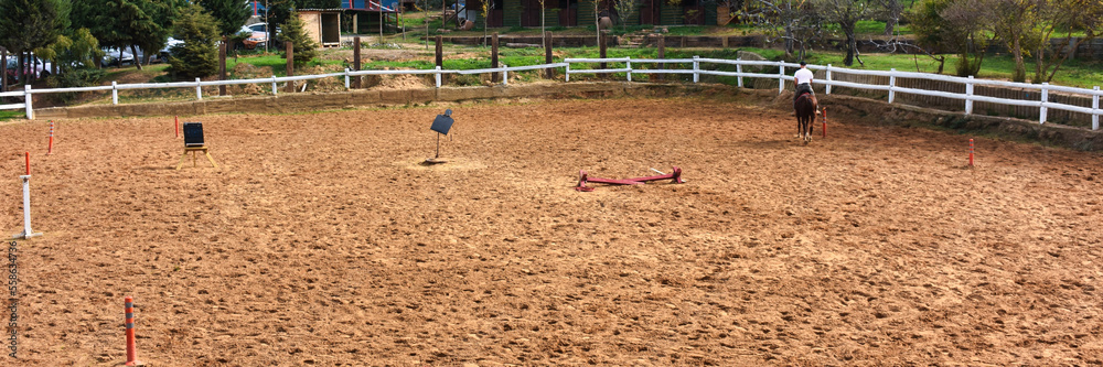 A man riding a horse with his back turned, is training with a horse at the horse farm.