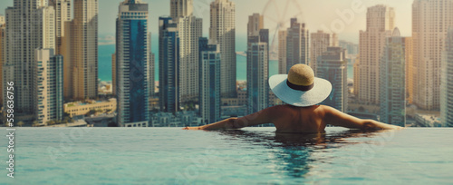 Photography woman enjoying Dubai marina skyline from luxury hotel infinity pool
