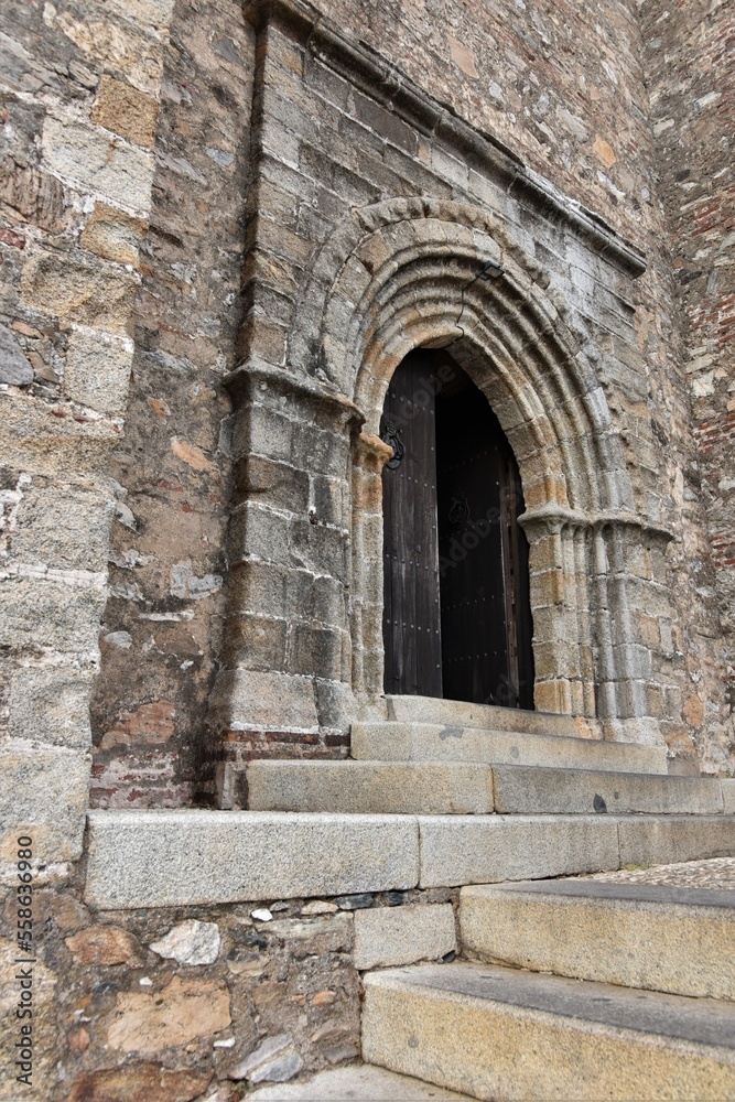 Super rustic heavily patinated stone portal in grey, yellow and white tones with some bricks mixed in at Iglesia Prior de Nuestra Señora del Mayor Dolor church, Aracena, Spain