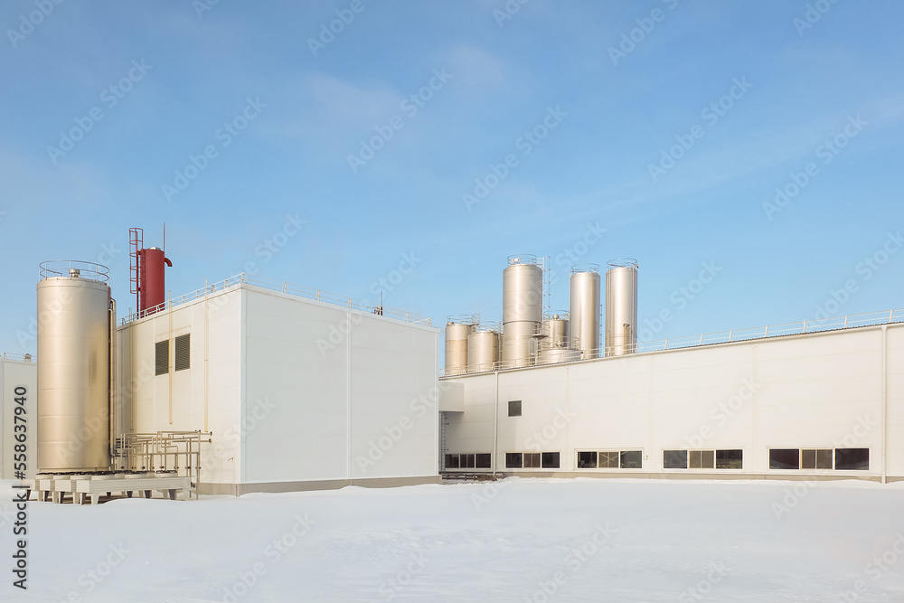 Agro industrial building with outdoor air conditioning units and vertical storage tanks for dairy products