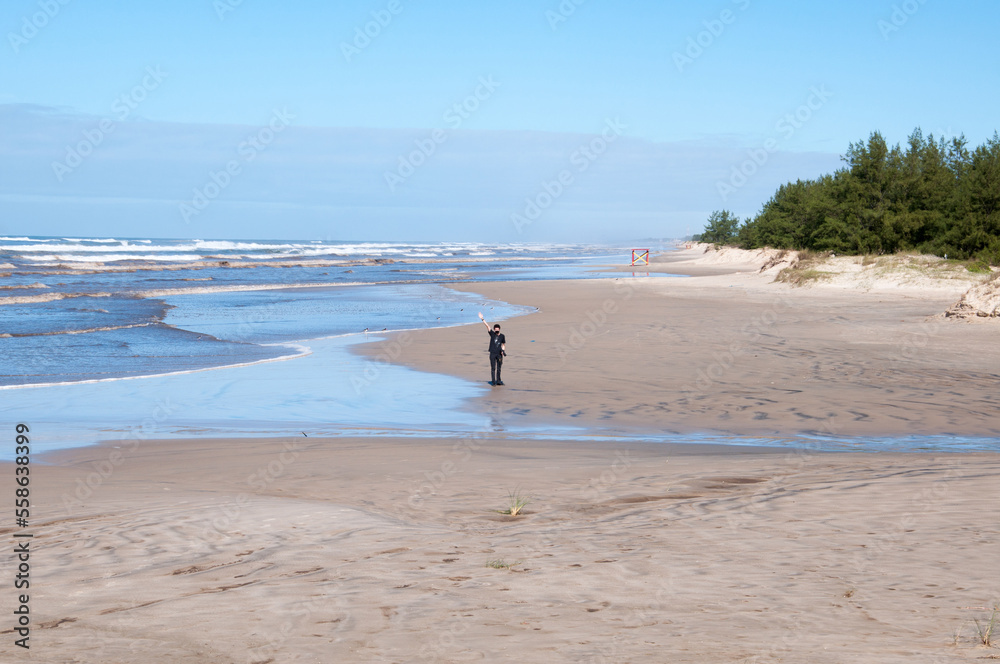 Young man waving on the beach
