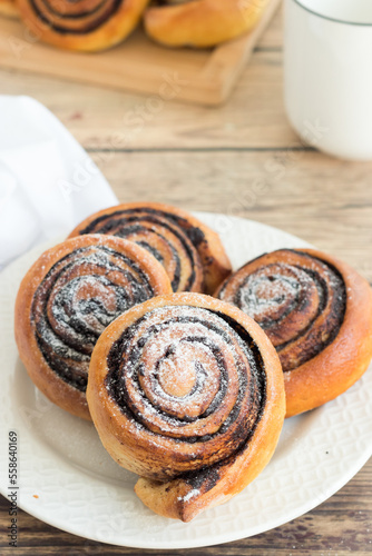 Sweet, homemade chocolate rolls served on a kitchen table with a glass of milk