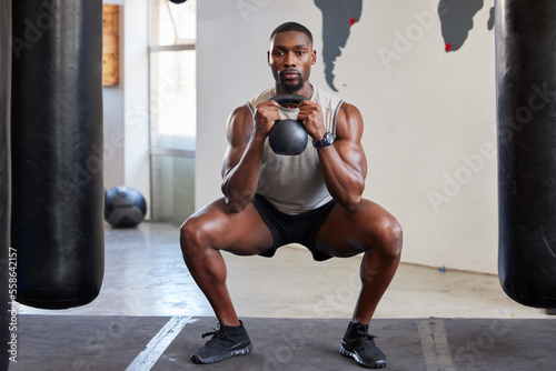 Black man, kettlebell squats and exercise in gym, fitness club and sports workout. Strong athlete, bodybuilder and muscle power with weight training, lifting and energy, wellness or healthy lifestyle
