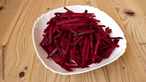 Raw peeled beetroot red rotate in a white plate on a wooden table. Beetroot red without skin. Cooking concept.