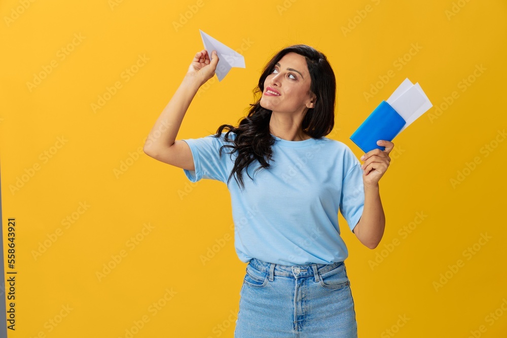 Traveler woman with yellow suitcase, passport and ticket in hand, paper plane, blue t-shirt and jeans on yellow background tourist, travel happiness, glasses, copy space Traveler woman with yellow suitcase, passport and ticket in hand, paper plane, blue t-shirt and jeans on yellow background tourist, travel happiness, glasses, copy space