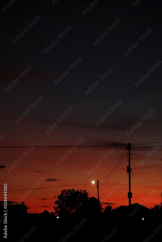 Dramatic colorful sunset sky with silhouette of a village.