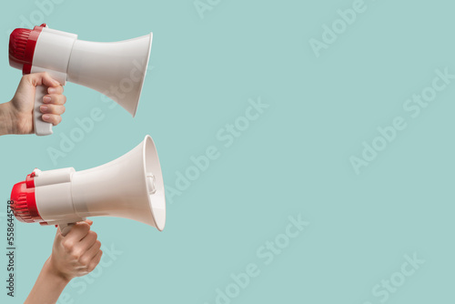 Megaphone in woman hands on a light green background.