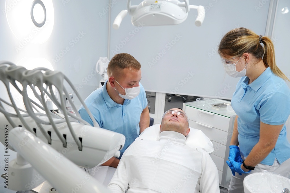 Obraz premium Close up of curing healing operating teeth tooth, filling mouth cavity against caries decay dentist orthodontist in dental clinic. Stomatology concept. man and young male dentist dental clinic