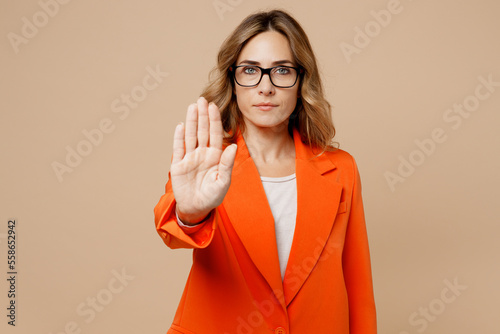 Young strict sad employee business woman corporate lawyer 30s wears classic formal orange suit glasses work in office showing stop gesture with palm reject isolated on plain beige background studio.