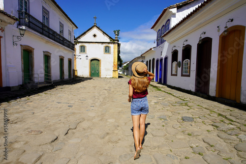 Cultural tourism in Brazil. Travel woman walking towards the chapel of Nossa Senhora dos Remedios e Sao Benedito in the historic village of Paraty, UNESCO World Heritage Site, Rio de Janeiro, Brazil. photo