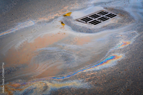 Oil slick on the asphalt road background drains into the storm drain.Water pollution environmental problems.